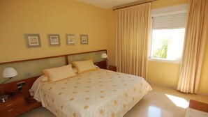 A bedroom with a bed, bedside tables, lamps, a window with curtains, and framed pictures on the wall. - Villa "Casa Heidi" with Sea View, Pool, Balcony, Air Conditioning & Wi-Fi (Almunecar)
