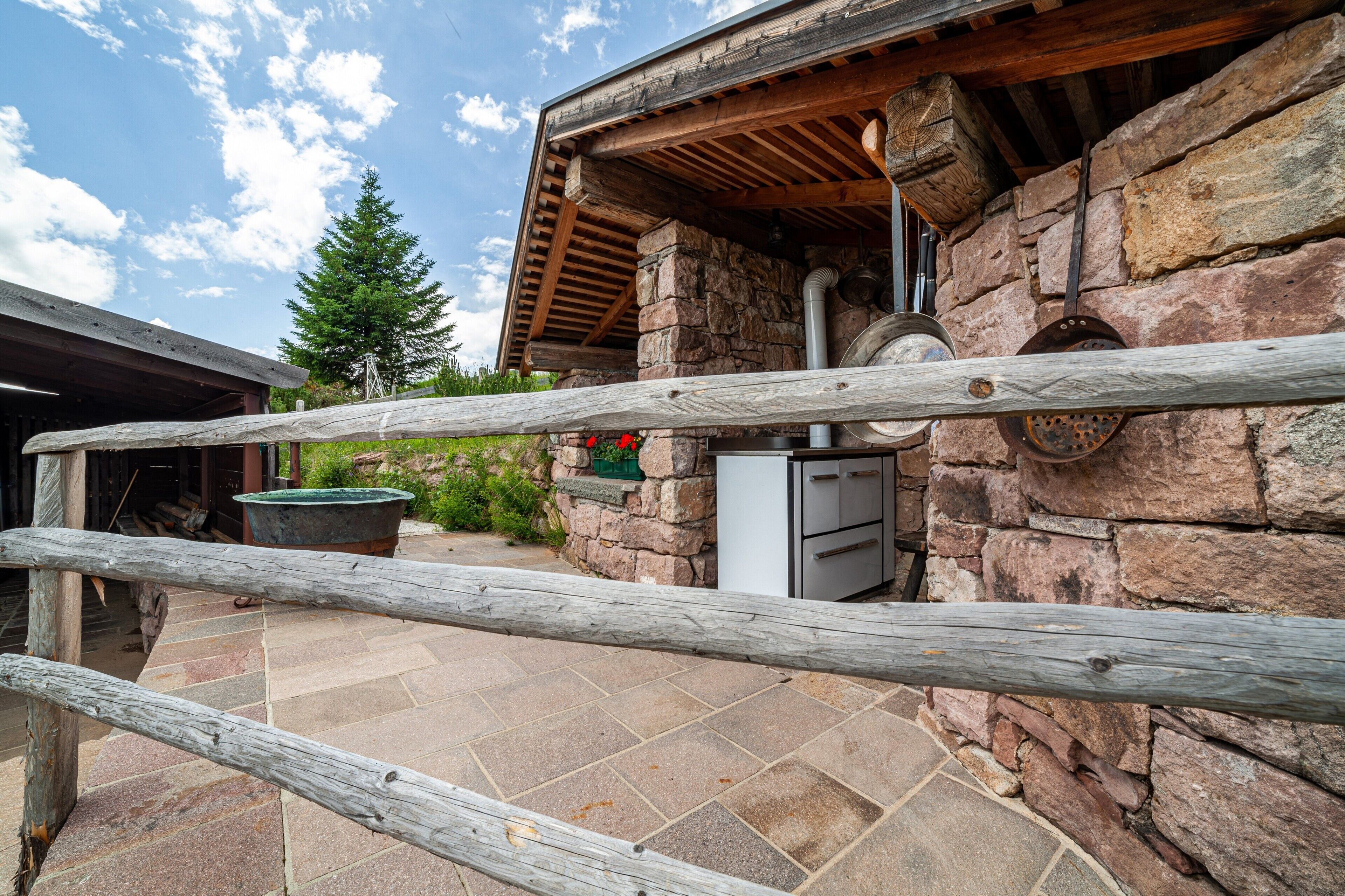 A stone building with a wooden roof, a stone chimney, and a metal door.