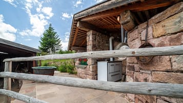 A stone building with a wooden roof, a stone chimney, and a metal door.