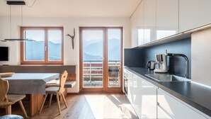 Une cuisine moderne avec un coin repas, de grandes fenêtres et une vue sur les montagnes.