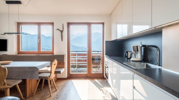 Eine moderne Küche mit Essbereich, großen Fenstern und Bergblick.