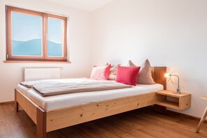 Et soveværelse med en træseng, et natbord, en lampe, et vindue med udsigt og en radiator.