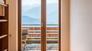 Ein Zimmer mit einer Holztür, die auf einen Balkon mit Bergblick führt.