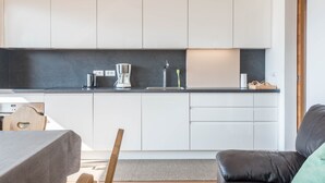 Eine moderne Küche mit weißen Schränken, einer schwarzen Arbeitsplatte und einer Kaffeemaschine.