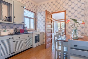 Une cuisine avec des armoires blanches, un fourneau et une porte en bois.