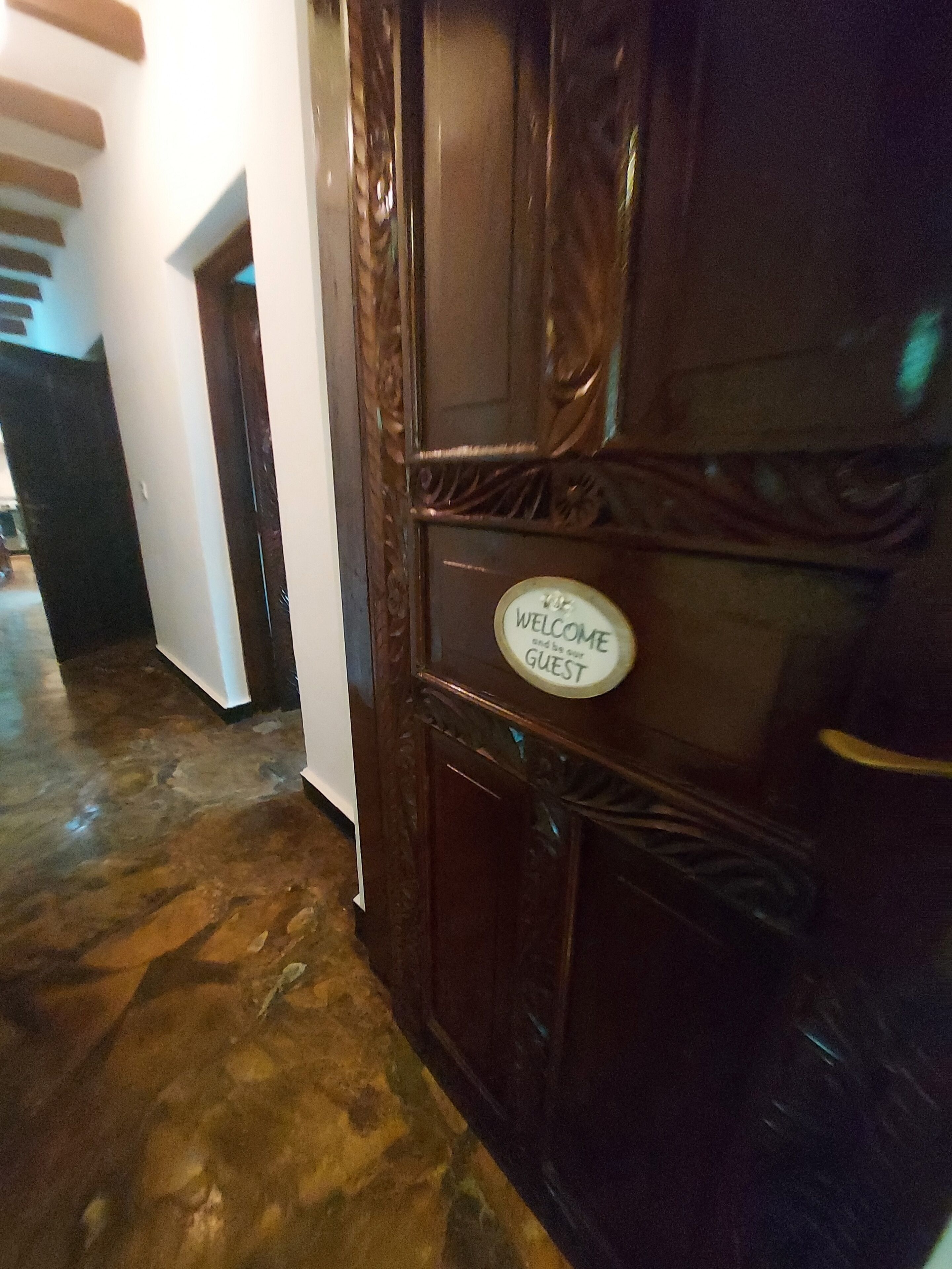 A wooden door with a 'Welcome and be our guest' sign.