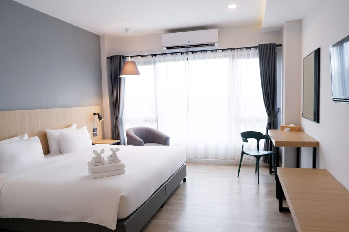 A modern hotel room with a large bed, a desk, and a chair.