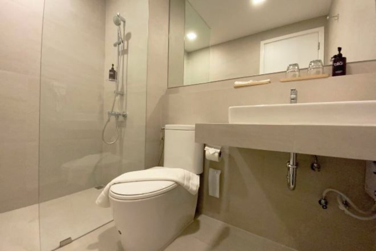 A modern bathroom with a toilet, shower, and sink.