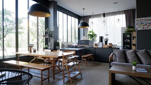 A modern living room with a wooden dining table, a sofa, and a coffee station. - bliQ Hotel Chanthaburi (Chanthaburi)