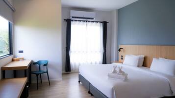 Una habitación de hotel con cama, escritorio, silla y unidad de aire acondicionado.