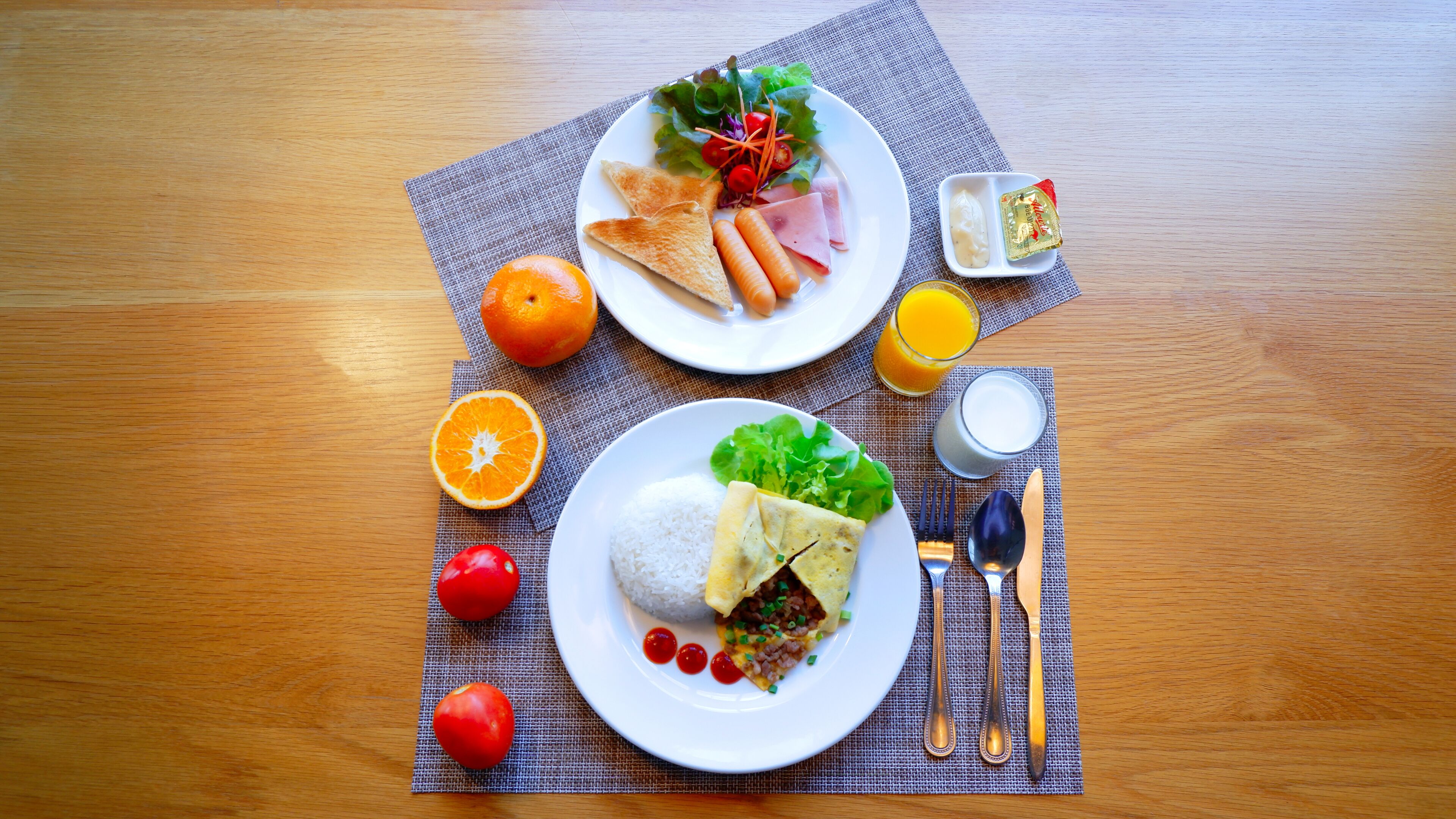 Uma mesa de madeira com apoio para pratos, exibindo uma refeição de café da manhã, incluindo torradas, ovos e vegetais.