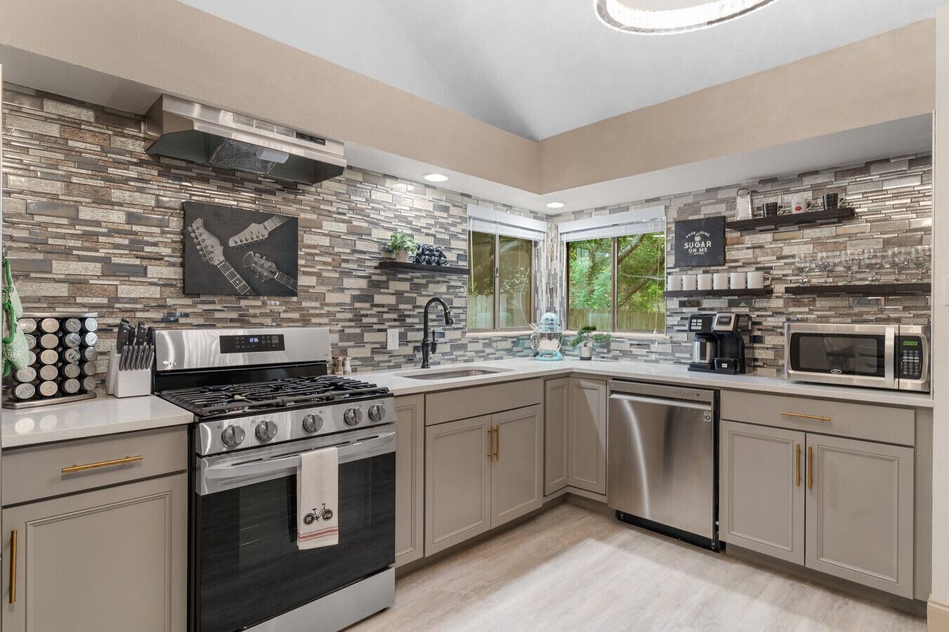 Fully stocked kitchen blends quartz counters, stainless appliances, and bold tilework, creating a stylish space for cooking and gathering at Good Vibes Roll.
