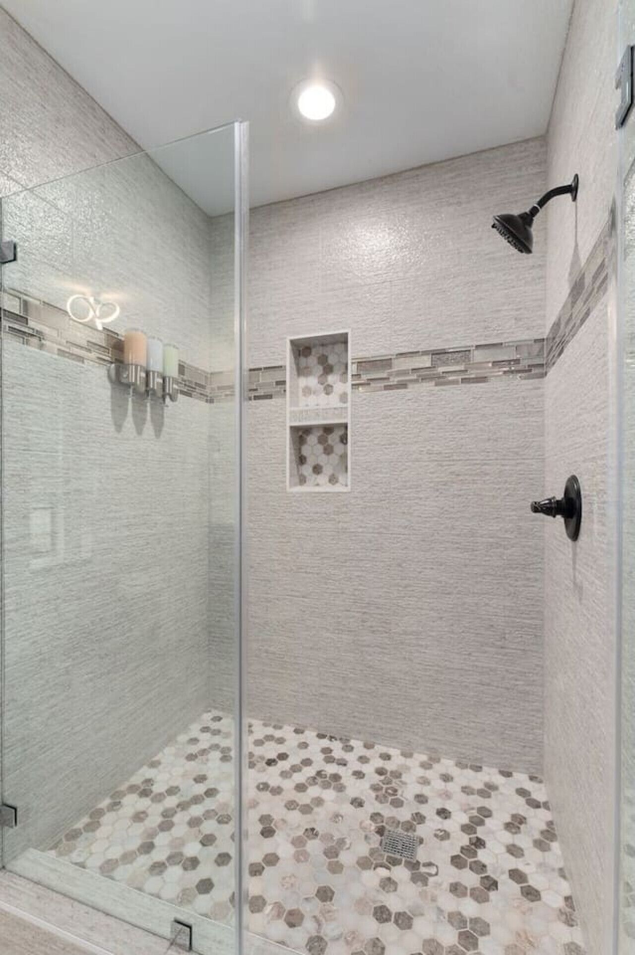 Une douche entièrementClose in glass, dotée d’un sol carrelé en forme d’hexagone et d’un éclairage encastré au plafond.