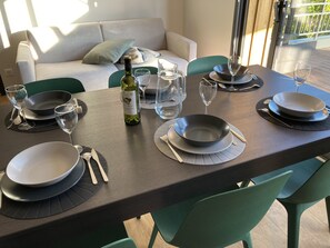 A dining table set with plates, bowls, cutlery, and wine glasses, with a bottle of wine and a pitcher of water.