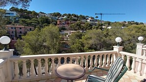 Ein Balkon mit Tisch und Stuhl, mit Blick auf ein Wohngebiet mit Häusern und Bäumen.