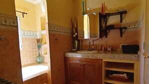 Ein Badezimmer mit Fliesenboden, Holzschränken, einem Waschbecken und einem Spiegel über der Ablagefläche.