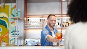 A bar area with a bartender serving a drink. - Holiday Inn - the niu, Hub Dusseldorf Messe by IHG (Düsseldorf)