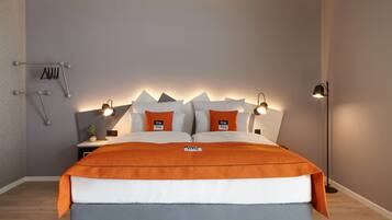 Ein modernes Schlafzimmer mit einem Bett, zwei Nachttischlampen, einem Nachttisch und einem an der Wand befestigten Handtuchhalter.