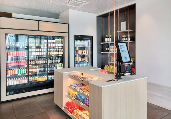 Un área comercial moderna con exhibidores refrigerados para bebidas y estantes con aperitivos.
