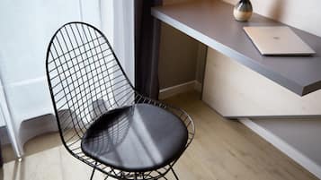 Una silla moderna con respaldo y asiento de malla negra, ubicada junto a un escritorio blanco con una computadora portátil.
