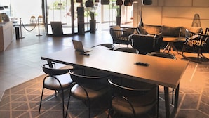 A modern hotel lobby with a long reception desk, several seating areas, and large windows allowing natural light. - Holiday Inn - the niu, Hub Dusseldorf Messe by IHG (Düsseldorf)