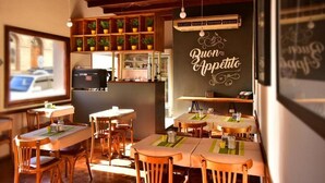 Un restaurante acogedor con muebles de madera y una pared de pizarra que muestra 'Buon Appetito'.