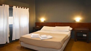 Habitación de hotel con cama, dos mesitas de noche, cortinas y luces en la pared.