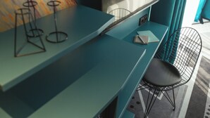 A teal-colored bar area with a black chair and stools. - Holiday Inn - the niu, Flash Berlin Charlottenburg by IHG (Berlin)
