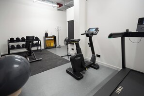 A gym with exercise equipment including a treadmill, a stationary bike, and a weight rack.