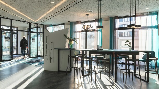 A modern interior with a bar area, seating, and large windows. - Holiday Inn - the niu, Flash Berlin Charlottenburg by IHG (Berlin)