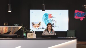 A reception desk with a screen displaying various design elements like graffiti and illustration. - Holiday Inn - the niu, Flash Berlin Charlottenburg by IHG (Berlin)