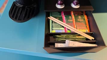 Une machine à café de la marque Jacobs, deux tasses et un plateau contenant des sachets de thé et des baguettes.