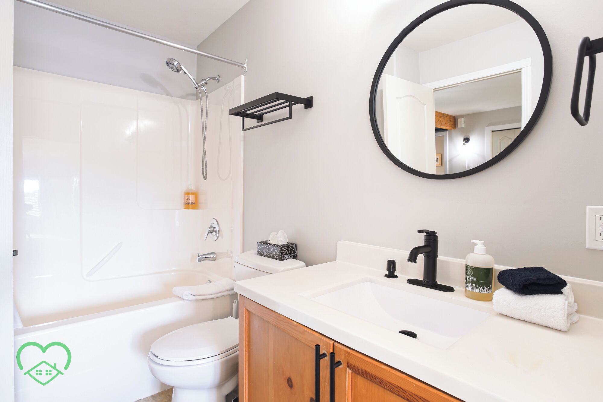 A modern bathroom with a shower, toilet, sink, and mirror.