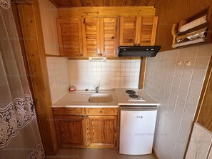 A compact kitchen with wooden cabinets, a white sink, and a white refrigerator.