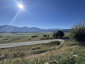 Ländliche Landschaft mit blauem Himmel, einer Straße und Bergen in der Ferne.
