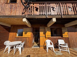 A wooden building with a balcony, a bicycle, and outdoor seating.