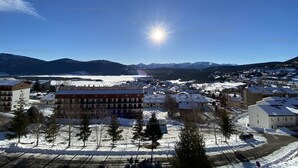 Une ville enneigée, avec des bâtiments et des montagnes en arrière-plan.