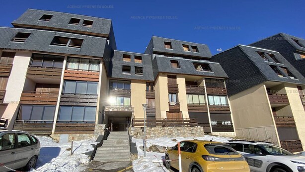 Un bâtiment moderne doté de nombreux balcons et d’un espace de stationnement enneigé.