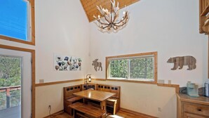 Een kamer met een houten eettafel, bankjes, een kroonluchter en dierenornamenten aan de muur.