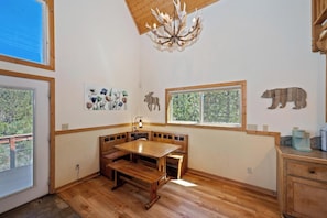 A room with a wooden dining table, bench seating, a chandelier, and wall-mounted animal decorations. - Beautiful Boulder Bay Setting & Lake Views! Game Room! HOT TUB! (Big Bear Lake)