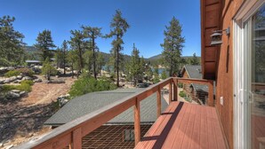 Un terrazza in legno con vista su un lago e alberi circostanti.