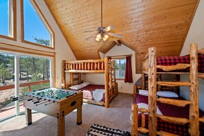 A room with bunk beds, a foosball table, and a ceiling fan. - Beautiful Boulder Bay Setting & Lake Views! Game Room! HOT TUB! (Big Bear Lake)