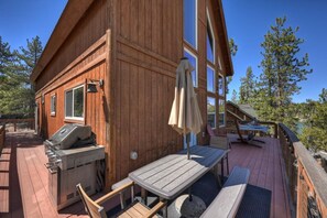 Une cabane en bois dotée d’une terrasse, d’un barbecue et de meubles pour se détendre à l’extérieur.