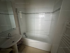 Un baño con bañera, lavamanos y espejo.