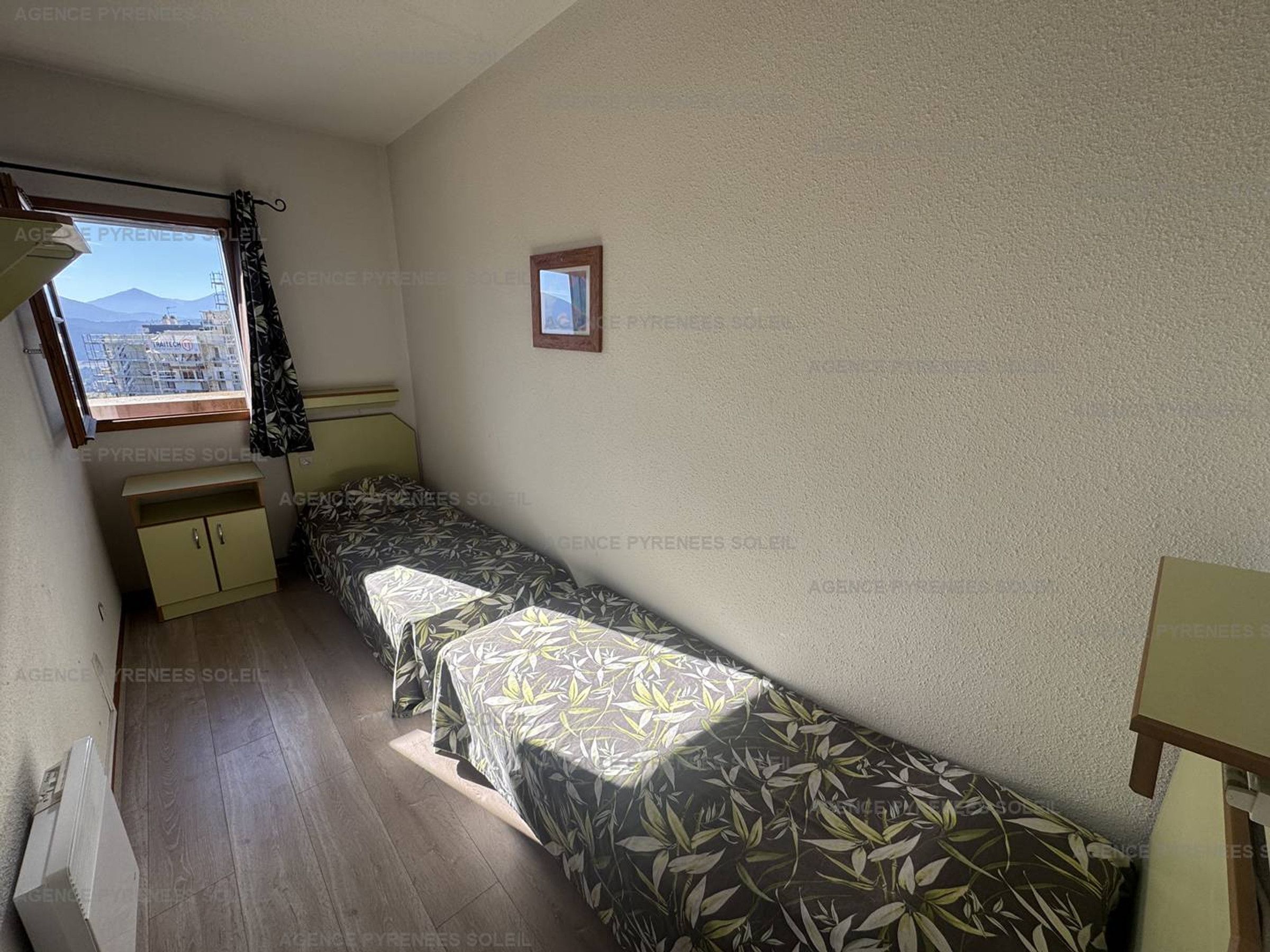 Eine kleine, einfache Unterkunft mit einem Bett, einem Tisch, einem Fenster mit Blick und einer Heizung.