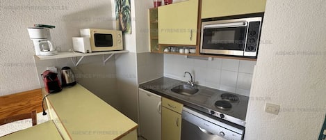 A compact kitchen with a microwave, stove, sink, and dishwasher.