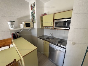 Cocina compacta equipada con microondas, estufa, fregadero y lavavajillas.
