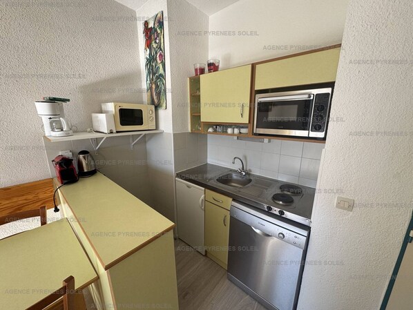 A compact kitchen with a microwave, stove, sink, and dishwasher.