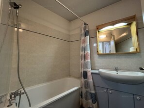 A bathroom with a bathtub, a shower, a sink, and a mirror.