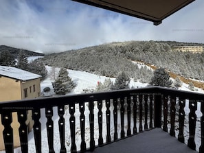A balcony with a view of a snow-covered landscape, including trees and a building.